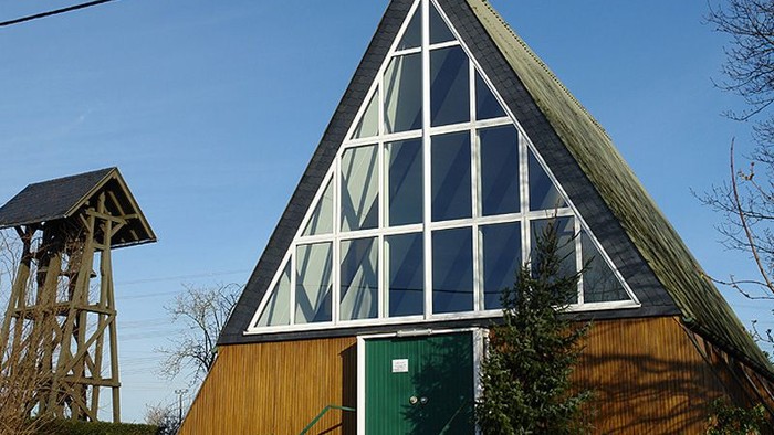 Ein modernes Holzhaus mit großen Glasfenstern und einer grünen Tür.
