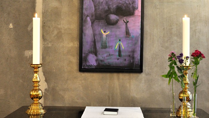 Billedet viser et indretning med maleri, lysestage og blomster i en rum.