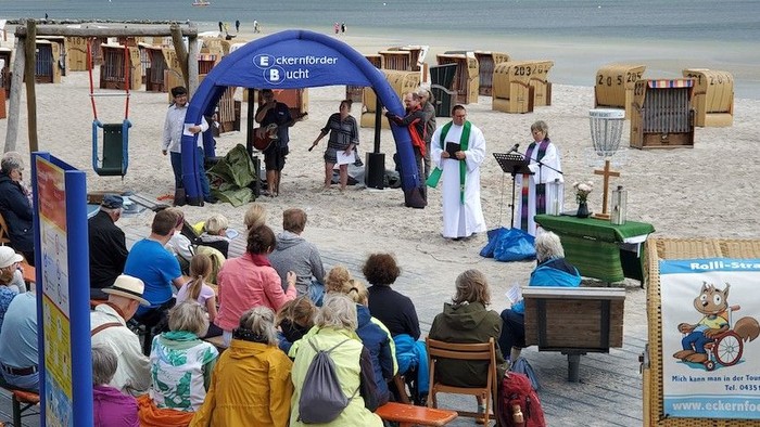 Strandveranstaltung mit vielen Menschen und einem Stand mit Informationsmaterial