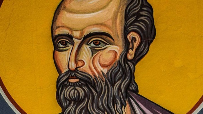 Billedet viser et portræt af en mand med lang barbe og skæg, omgivet af guld og svart.