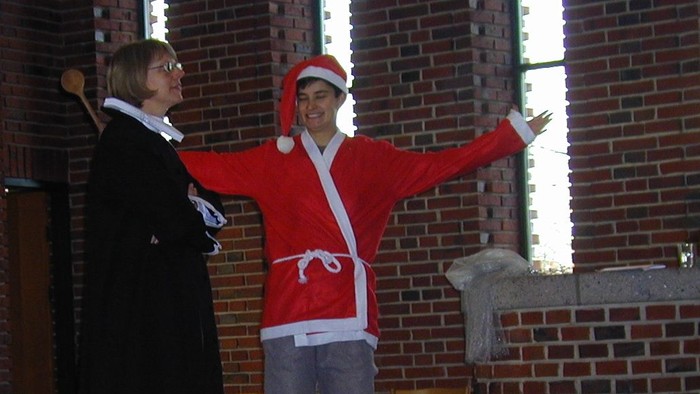 En mand i Santa-kostume og en kvinde står foran en gruppe børn.