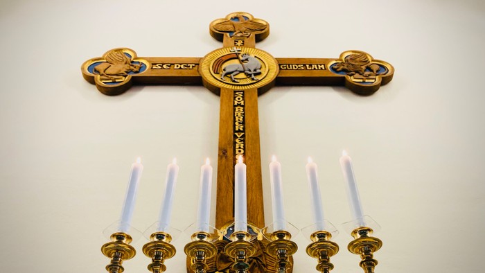 Guldfarvet kors med lysstake og lys foran