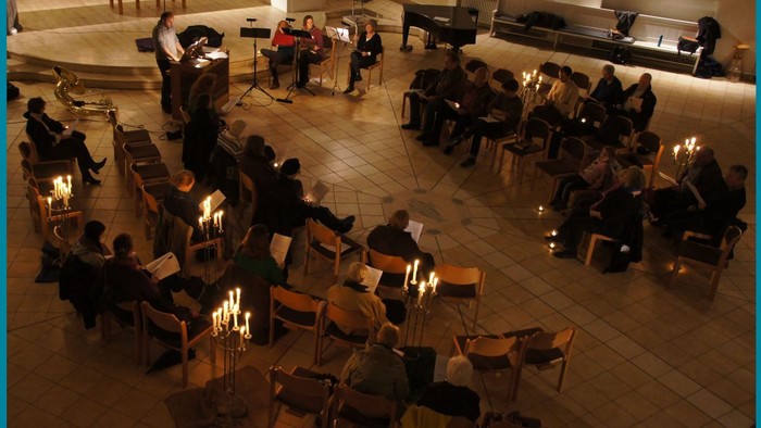 Ein gut beleuchteter Raum mit mehreren Tischen und Stühlen, an denen Menschen sitzen.