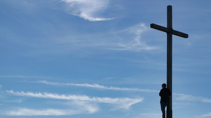 Mensch auf einem Berg mit Gipfelkreuz