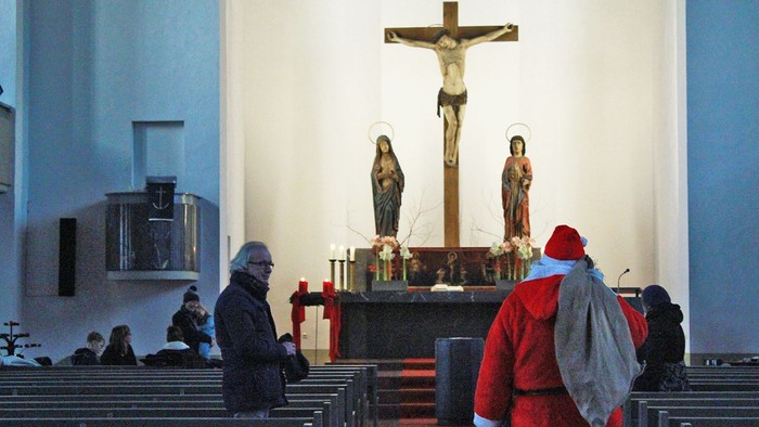 In der Kirche beten zwei Personen vor dem Altar mit Kruzifix.
