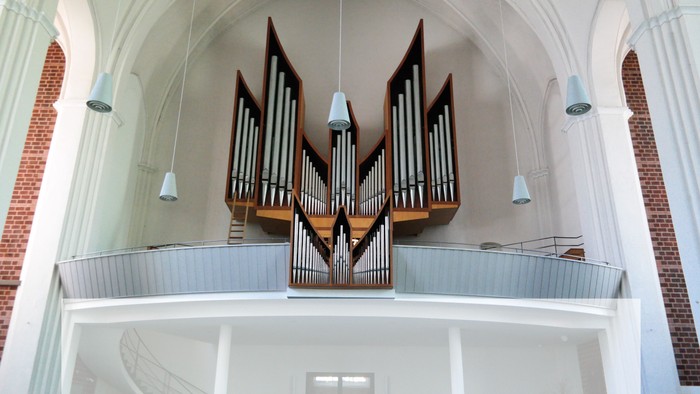 Orgel in einer Kirche mit weißen Wänden und roten Ziegeln