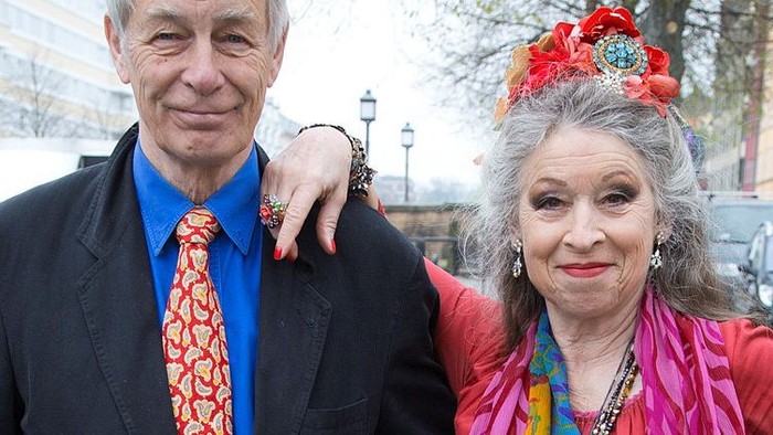 En mand og en kvinde poser til billede, begge smilende. Kvinden har en farverig kron og smukke tøj.