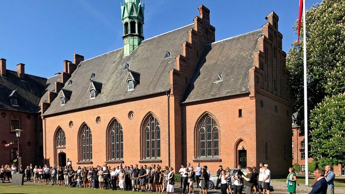 En stor kirke med spiret og en folkemængde foran.