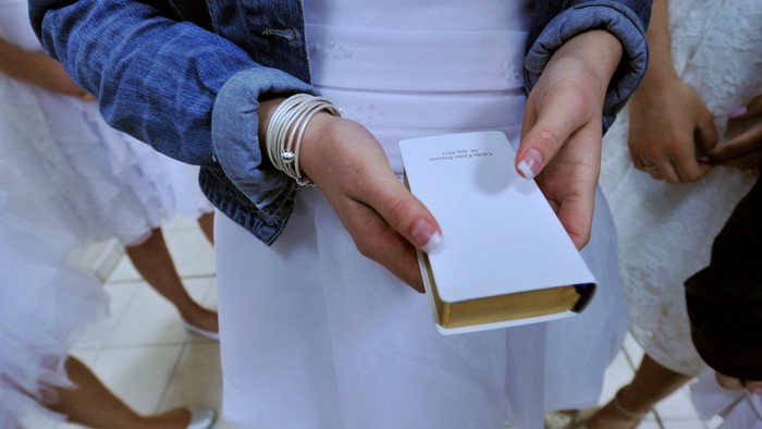 En person holder en hvid bog med bånd om.