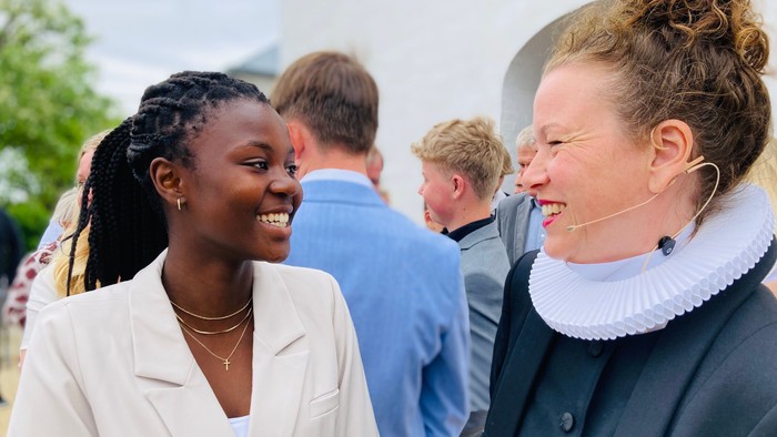 To kvinder står tæt på hinanden og smiler.