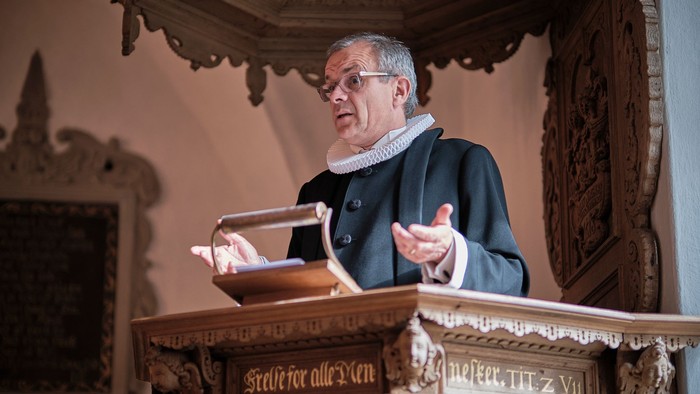 Mand preker fra pult i kirke