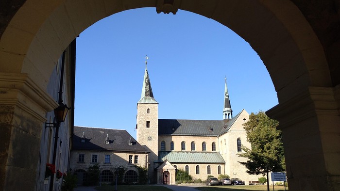 Durch den Torbogen sieht man eine Kirche mit zwei Türmen.