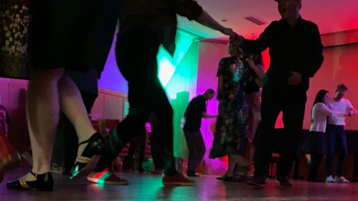 Eine Gruppe von Menschen tanzt in einem beleuchteten Raum.