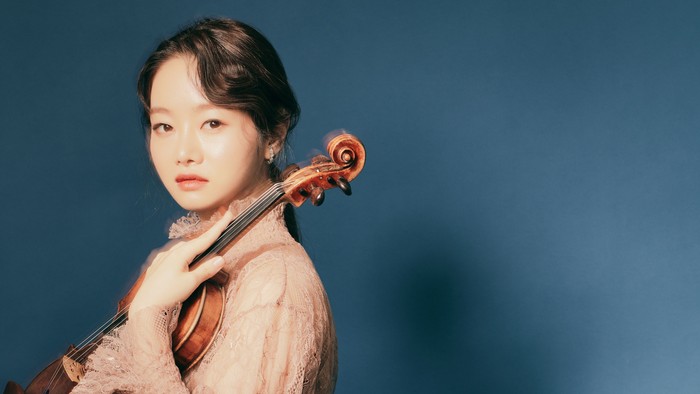 Junge Frau spielt Geige vor blauem Hintergrund