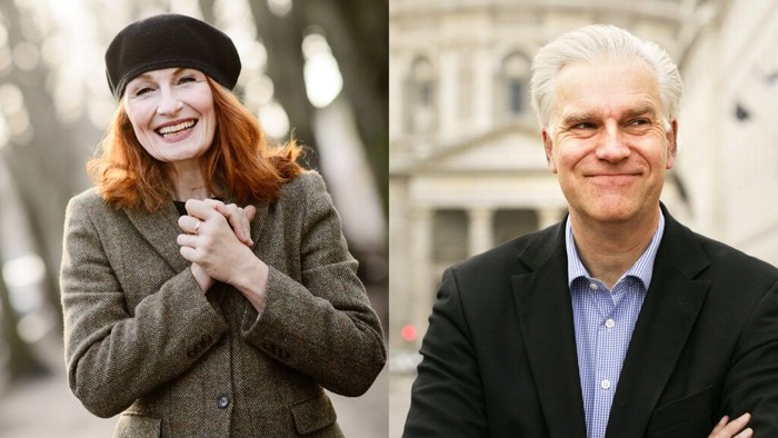 En kvinde med rødt hår og beret står i en bygate, en mand i mørk jakke smiler til kameraet