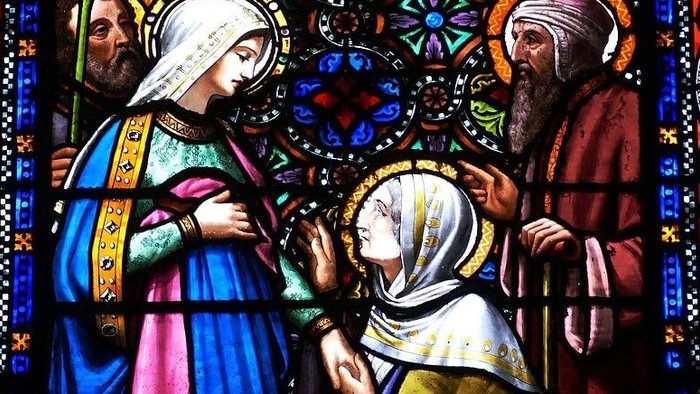 Glassmaleri af tre religiøse figurer i farverne blå, rosa og gul