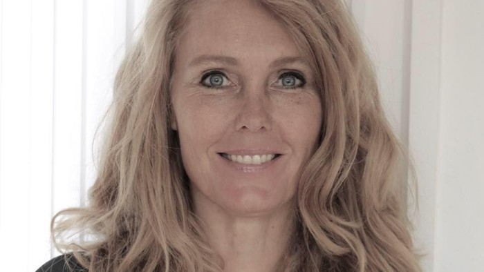 En kvinde med blondt hår og en sort bluse.