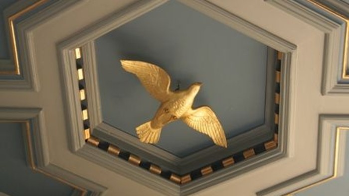 Gul fugl i blå og gyldne indramning på tak