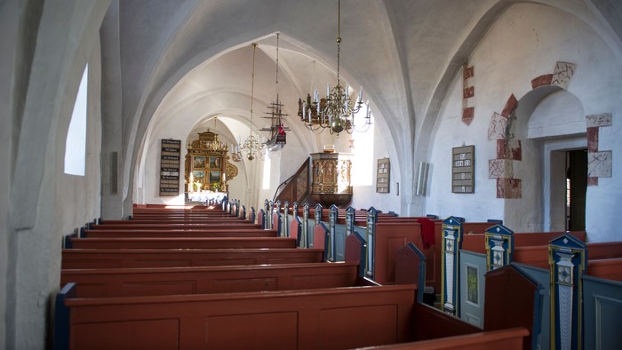 Indre del af kirke med træbænke og hængende lygter