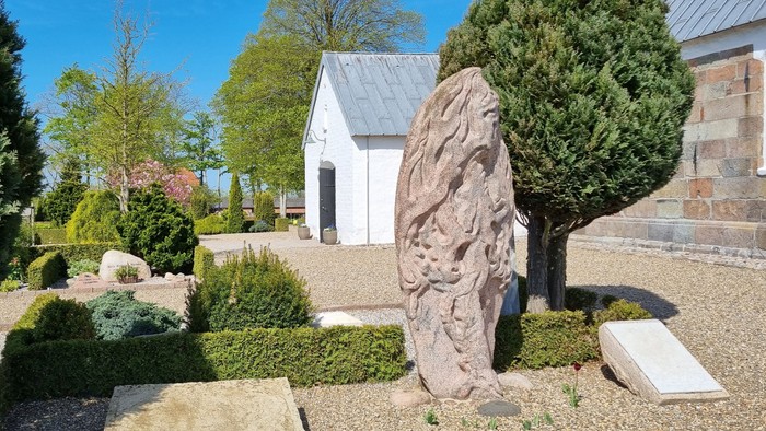 En lille kirke med en stenstatue og en træ i en have