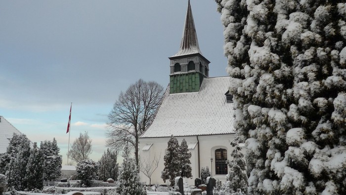 Snefaldt på kirke og træer i landsby