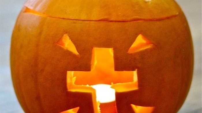 En udekkeret pumpa med en skåret korsformet munn og øjne.