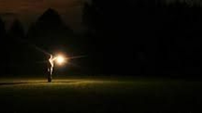 En person med lygte går gennem en mørk skov.