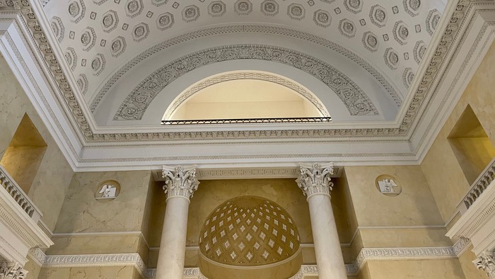 Indre del af en prægtig bygning med udsmukkede kolonner og indvandede dekorationer.