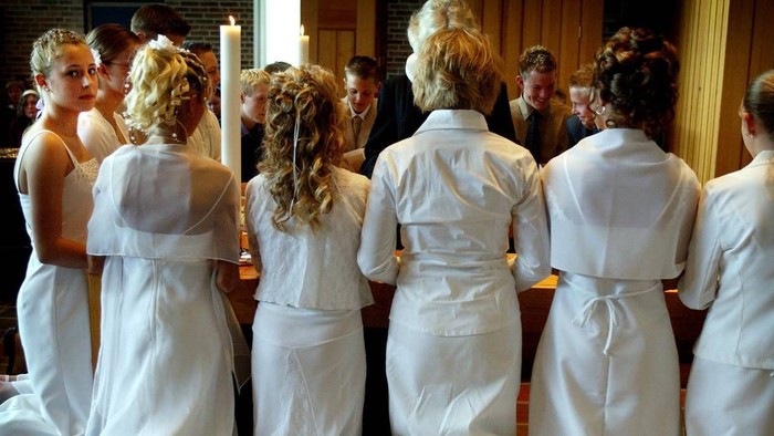 En gruppe kvinder i hvide tøjer og hårfrisyrer står sammen og snakker.