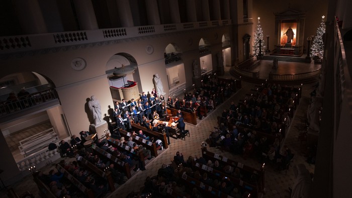 En stor koncertsal med publikum og orkester på scene