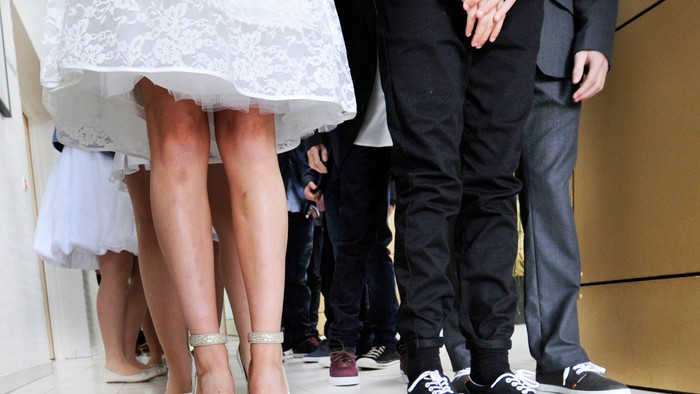 En brud og en gom i formelle klæder, sammen med andre gæster ved en fest.