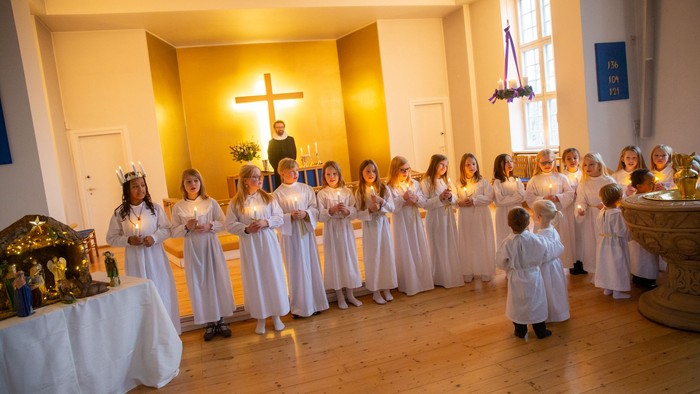 En gruppe børn i hvide tøjer deltager i en religiøs ceremoniel i en kirke.