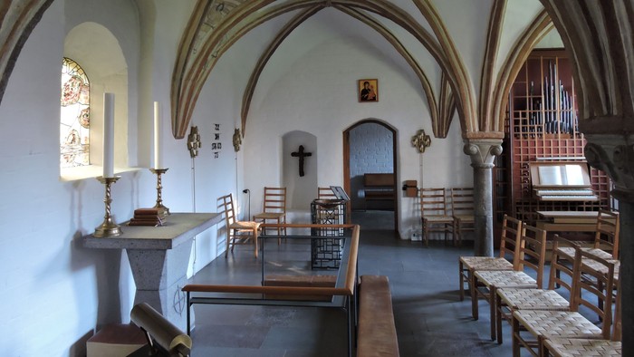 Kapel med hvidt tag, bænke, orgel og alter.