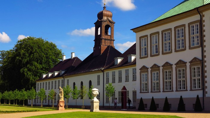 Stor, hvid og gule slott med klokketårn og grønne arealer