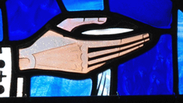 Stained glass artwork featuring a hand with water flowing, surrounded by geometric patterns and a cross