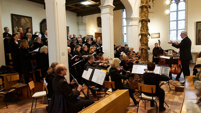 Ein Orchester probt in einer Kirche unter der Leitung eines Dirigenten