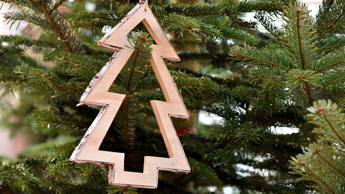 Ein hölzernes Weihnachtsbaum-Dekoration hängt an einem Tannenbaum.