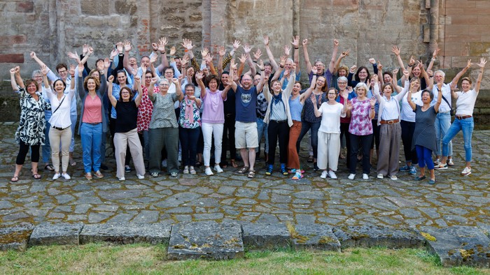 Eine Gruppe von Menschen feiert vor einer Steinmauer