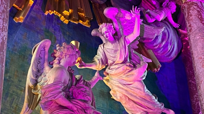 En udstøbt gruppe af figurer i en kirke, belysnet med farver.