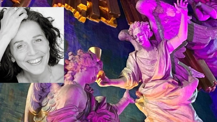 En kvinde i rosa kostume optræder på scenen med dramatiske og frodige gestuer