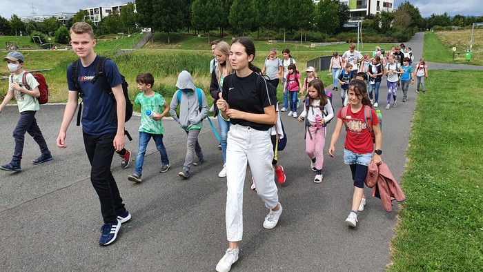 Eine Gruppe von Menschen, darunter Kinder und Erwachsene, geht auf einem Weg im Freien