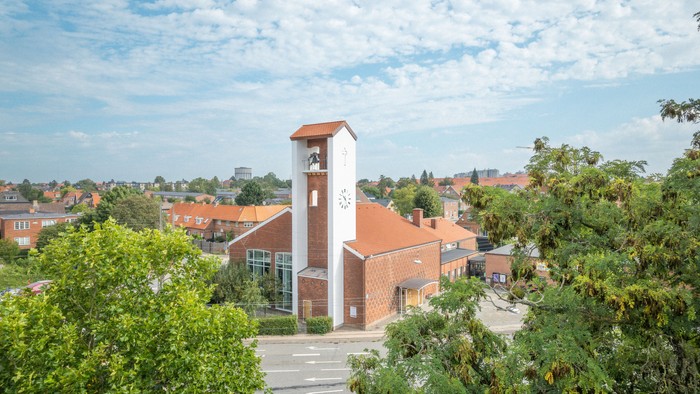 En kirke med klokketårn i en grøn og træfattig by.