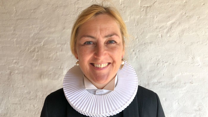 En kvinde med kort, blond hår og en hvid krage.