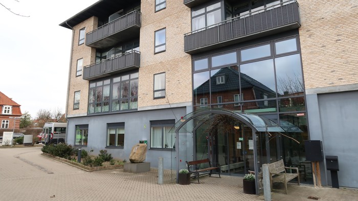 Moderne lejebolig med store vinduer og balkoner.