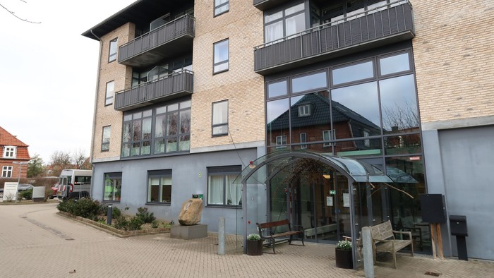 Moderne lejebolig med store vinduer og balkoner.