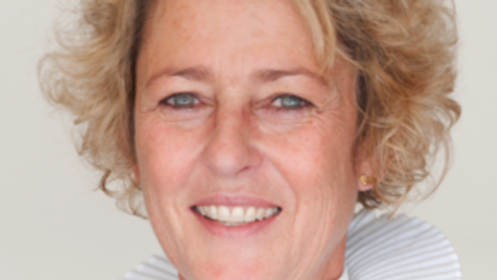 En kvinde med kort, blond hår og en smil.