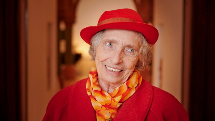 Alte Frau mit rotem Hut und Schal lächelt