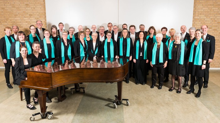 En gruppe af mænd og kvinder poserer sammen med et piano