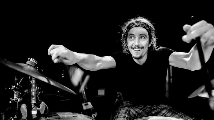 En mand spiller trommer med glade udtryk