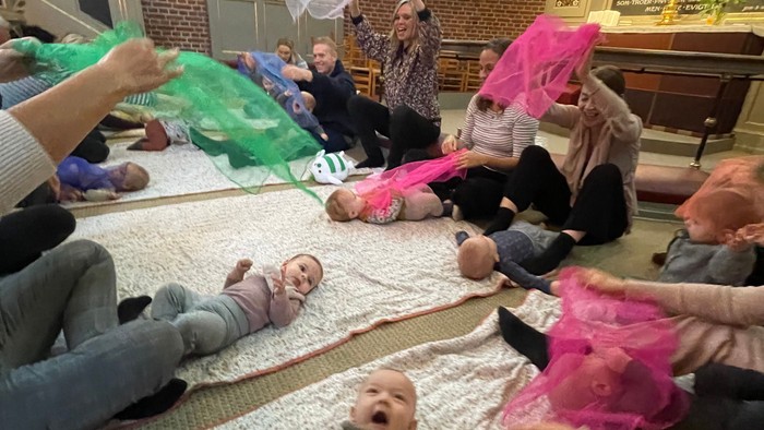 Børn og voksne spiller med paraplyer i kirke.